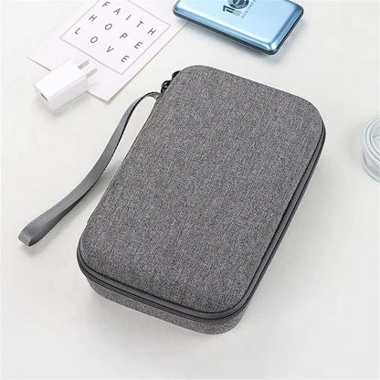 Large capacity grey travel electronics accessories organizer with zipper and wrist strap on white surface