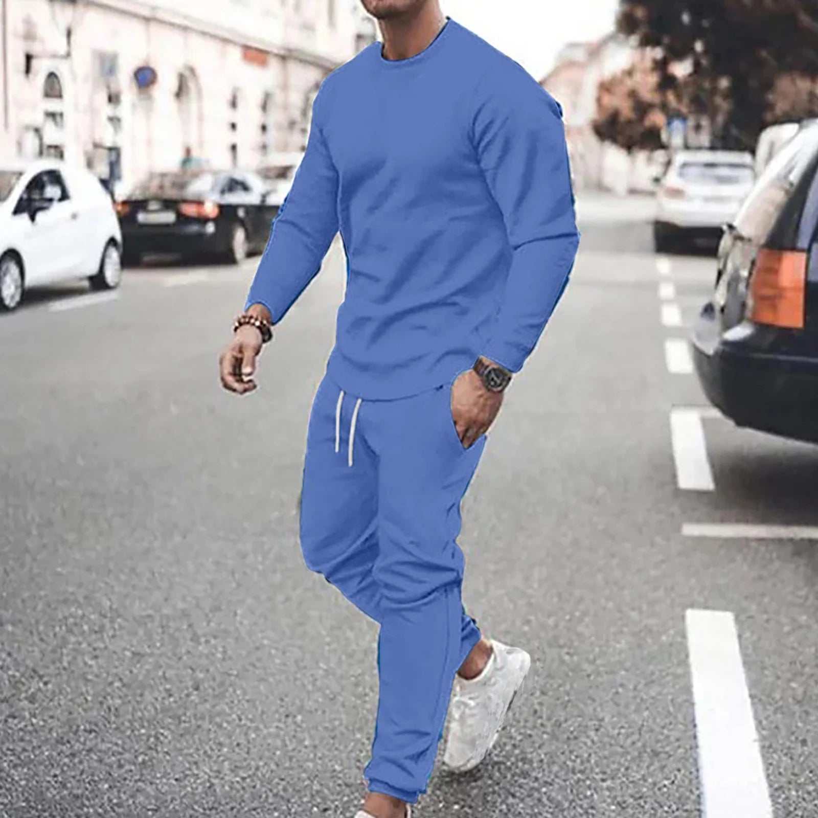 Man wearing blue casual sport pants with matching sweatshirt walking on city street